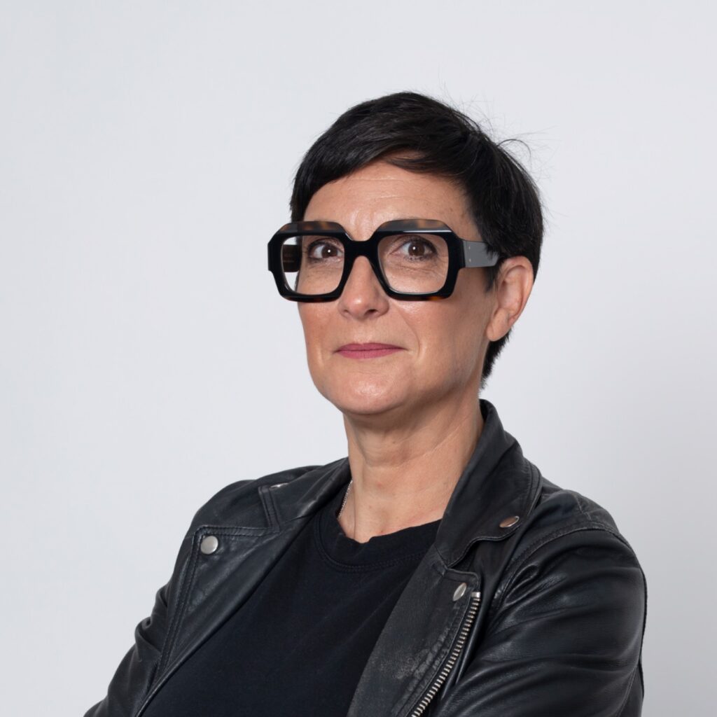 Portrait d'une femme experte en financement d'entreprise et crédit pro, avec des lunettes et une veste en cuir, symbolisant le conseil pour le choix entre capital social et compte courant d'associés.