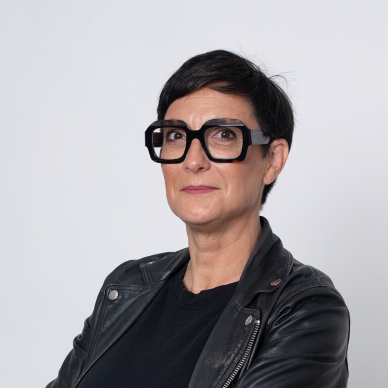 Portrait d'une femme experte en financement d'entreprise et crédit pro, avec des lunettes et une veste en cuir, symbolisant le conseil pour le choix entre capital social et compte courant d'associés.