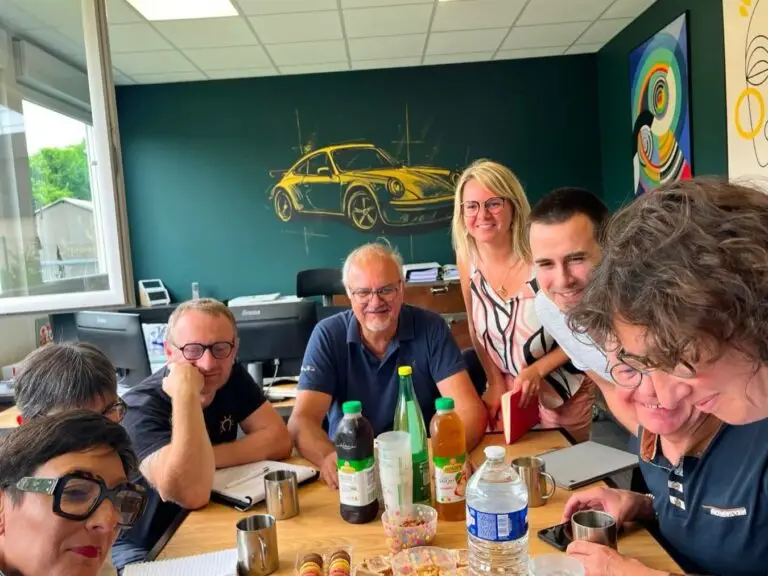 L'équipe PROFI à Reims souriante et collaborative autour d'une table, symbolisant l'approche humaine du financement professionnel pour les chefs d'entreprise, repreneurs, commerçants, artisans et professions libérales.